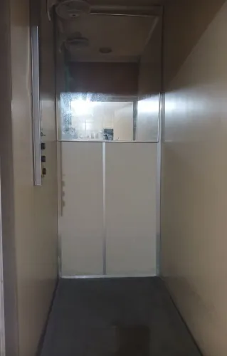 Elevador Residencial com painéis metálicos, espelho, ventilador e lâmpada.