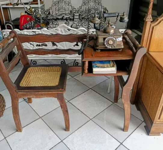 Antiga mesinha de telefone com assento de palha com telefone antigo