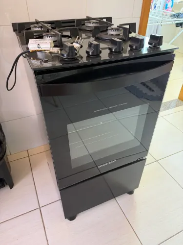 O fogão Brastemp 4 bocas preto, com mesa de vidro e grades duplas de ferro fundido
