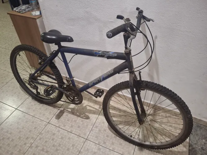 Bicicleta aro 26 e sistema simples de 18 marchas com freios V-brake.
