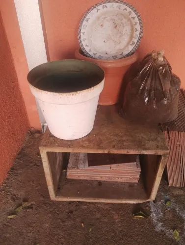 Dois baldes grande um saco de terra preta um prato grande e uma caixa para ar condicionado
