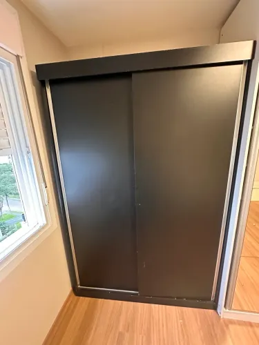 Roupeiro preto com portas de correr, gavetas e ótimo espaço interno