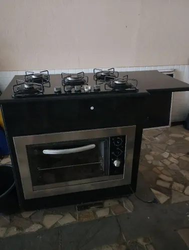 Cooktop com forno e gabinete de granito preto.