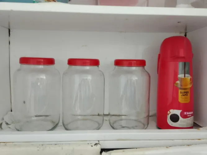 Três vidas grandes de armazenado alimentos e uma carrfa de colocar café vermelho