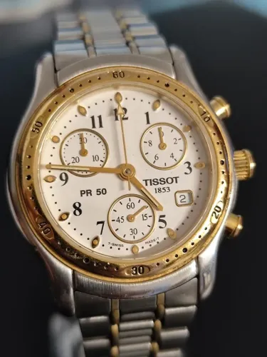 O relógio apresentado na imagem é um Tissot PR 50 Chronograph bicolor