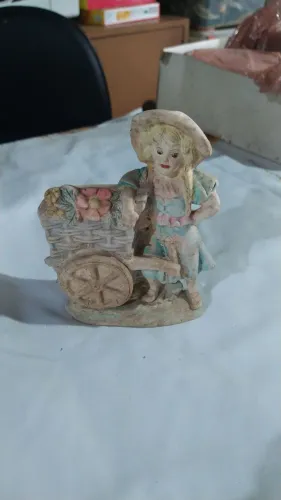 Escultura de menina com carrinho de flores