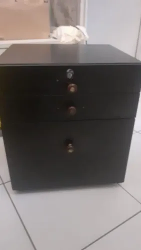 Gaveteiro preto com os puxadores no formato redondo e na cor marrom. 