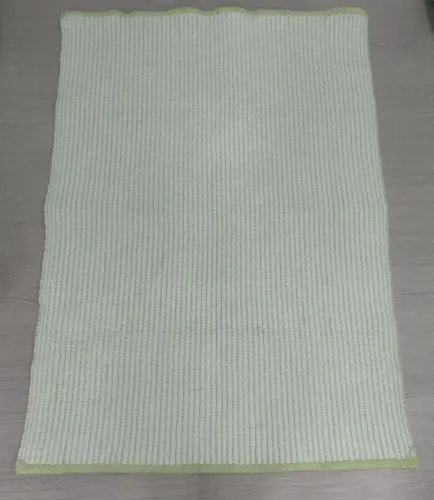 Tapete em tecelagem em tons de verde e branco.