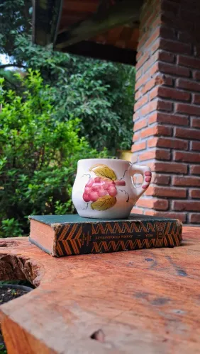Caneca de faiança antiga pintada à mão com decoração de cachos de uva.