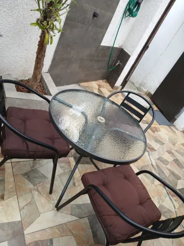 Mesa com vidro e três cadeiras com almofadas