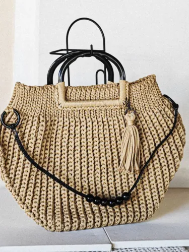 Bolsa de crochê com alças de plástico e de couro com acessórios. Possui tassel 49x36 cm