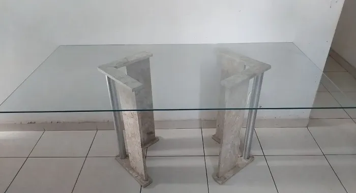 Uma mesa de vidro com duas bases de mármore 
