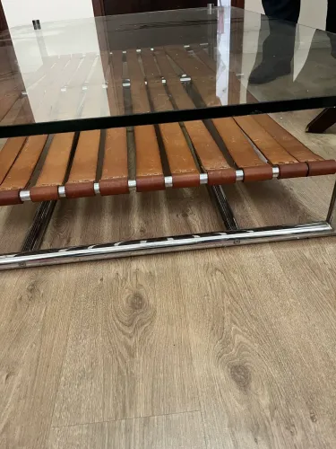 Mesa de centro com tampo de vidro, base inox detalhado em couro.