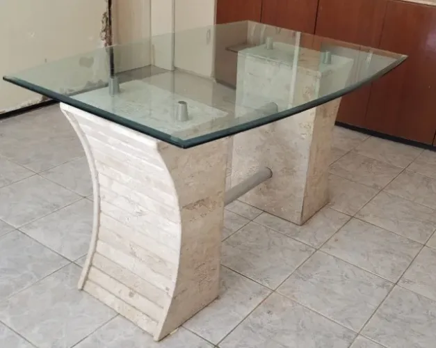 Mesa de vidro com base de mármore sem cadeiras.