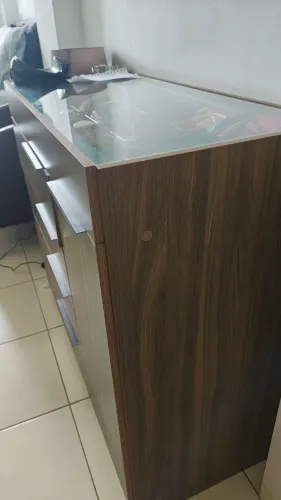Sapateira com tampo de vidro, gavetas e uma porta.