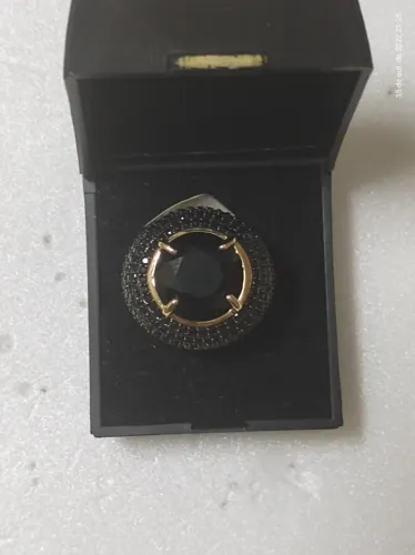 anel dourado com rubi negro e cravejado de incrustações de ônix