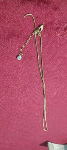 Cordão acho que e ouro está quebrado com uma pedra diamante.