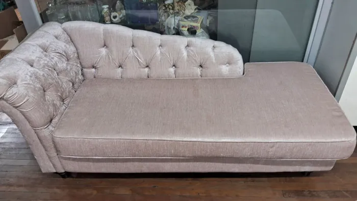Divã recamier em tom rosê possui estofamento aveludado com elegante acabamento em capitonê