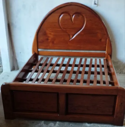 Cama de casal semi nova de madeira maciça com detalhe de coração na cabeceira.