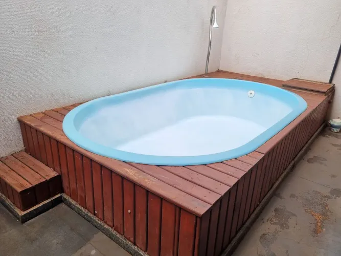 Piscina de fibra com aquecedor, estrutura de madeira e bombas.