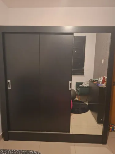 Guarda-roupa preto com três portas de correr e espelho