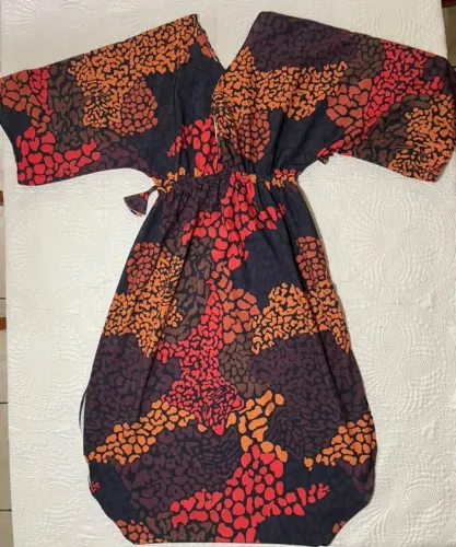 Vestido estampado com fundo escuro e detalhes em vermelho, laranja e vinho.