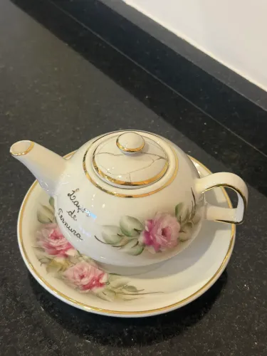 Mini bule decorativo em porcelana com pintura floral e detalhes dourados.