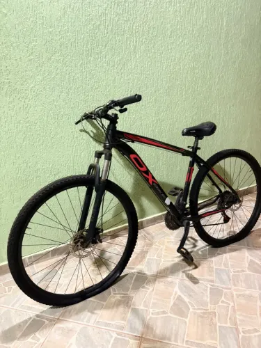 Esta é uma bicicleta mountain bike OX Glide aro 29 na cor preta com detalhes vermelhos.