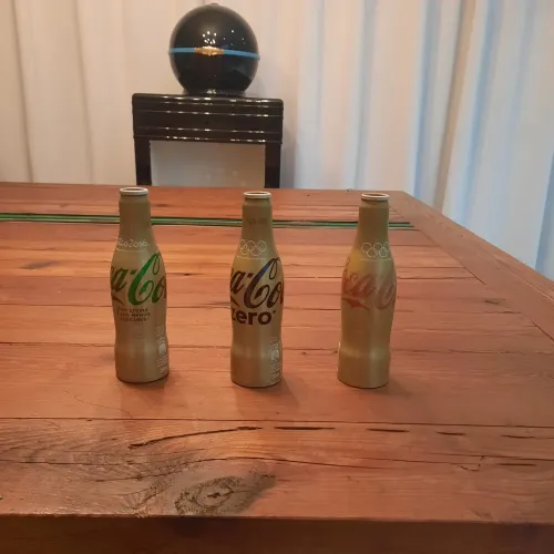 Tres garrafas colecionáveis douradas da Coca Cola 