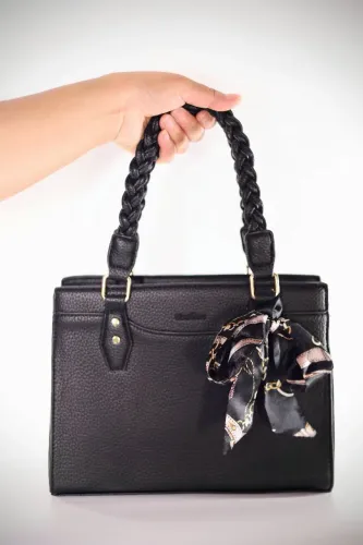 Bolsa de mão preta texturizada com alça trançada e lenço estampado.