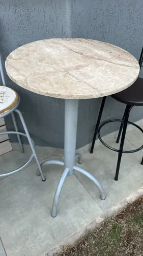 Mesa bistrô com tampo em granito e 2 banquetas metálicas.