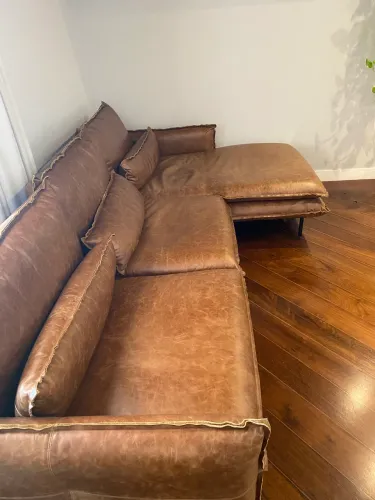 Sofá de couro com chaise, na cor marrom. 