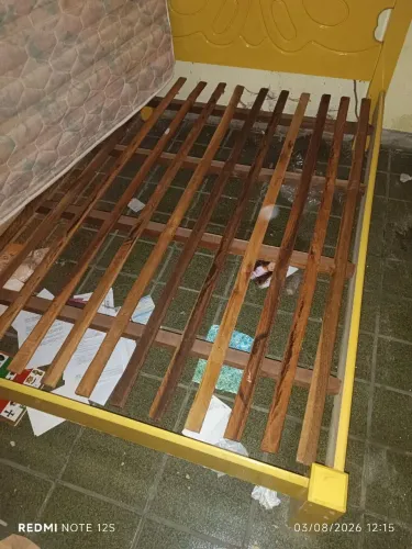 Cama de madeira amarela reforçada, pra sair rápido.