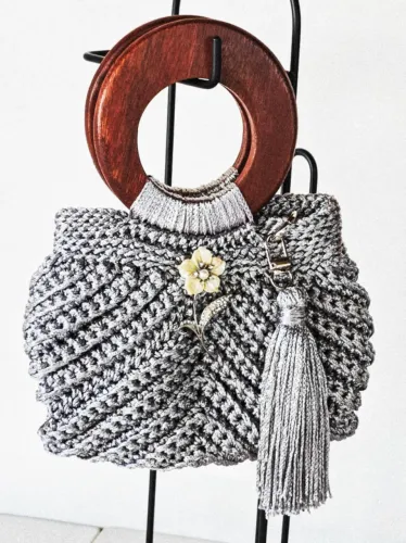 Bolsa de crochê de mão com alça de madeira e tassel.
