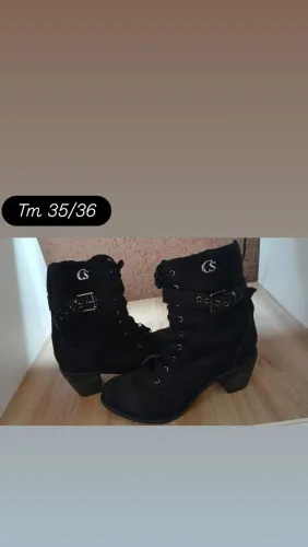 bota coturno preta Carmen Steffens, feita em camurça e com detalhe de fivela no cano.