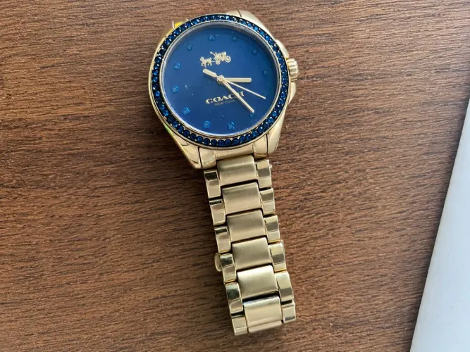 relógio original quartzo feminino Coach com mostrador azul e pulseira dourada.