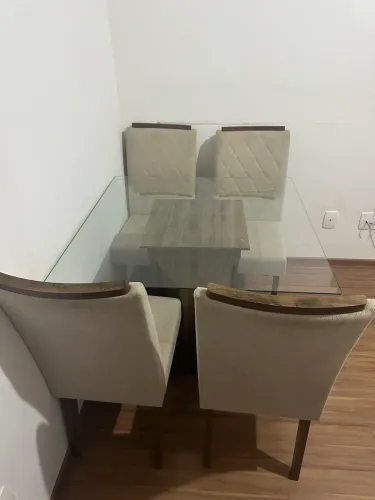 Mesa de jantar com 4 lugares, tampo de vidro e cadeiras em estofado bege.