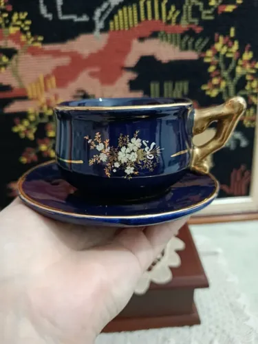 xícara de café vintage, azul cobalto, com detalhes florais e alça dourada.