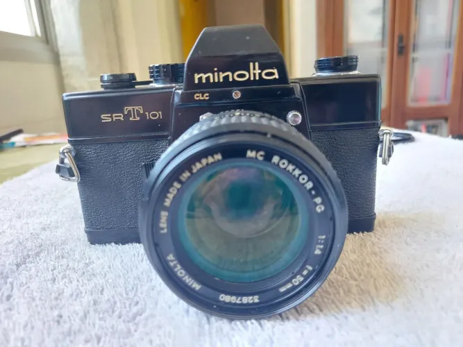 Câmera Minolta SRT 102 funcionando e com vários itens acompanhando. 