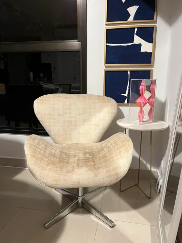 Poltrona estilo Swan com base giratória cromada e estofamento em suede bege