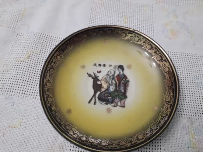 Prato decorativo oriental em porcelana, com cena chinesa, ideogramas e acabamento dourado.