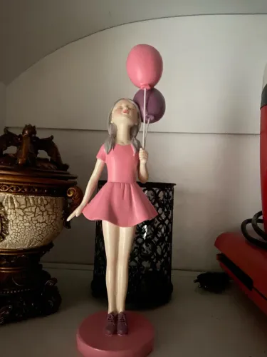 1 escultura menina segurando balões cor de rosa