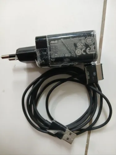 AD827M é um carregador/fonte de alimentação original da ASUS (15V / 1.2A, 18W). Ele utiliz