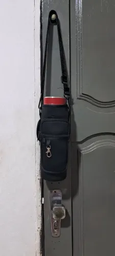 uma bolsa porta-copo ou garrafa térmica com alça ajustável e bolso frontal com zíper.