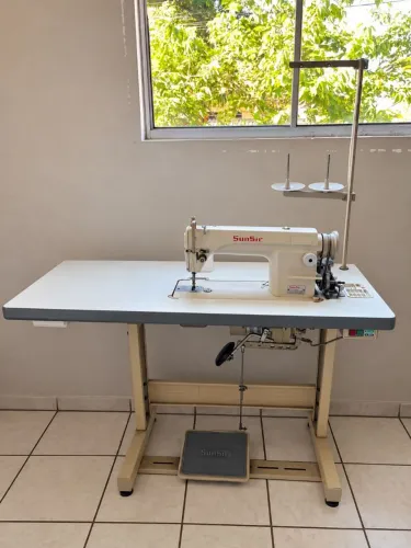 Máquina de costura reta industrial com diversos acessórios e linhas