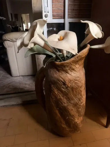 Vaso rústico em cerâmica com arranjo de copos de leite
