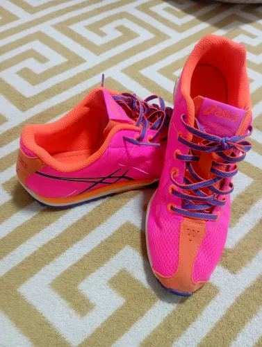Tênis de corrida Asics Cross Freak na cor rosa neon.