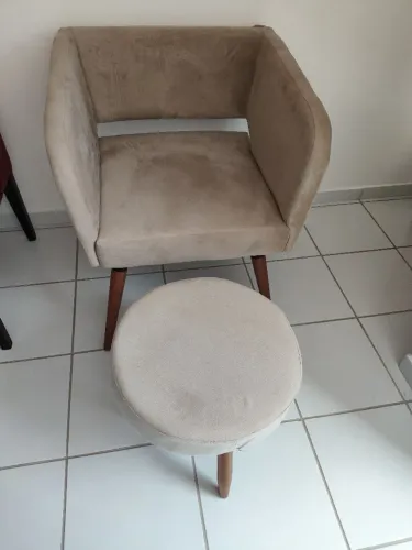 Poltrona bege com banquinho de apoio.