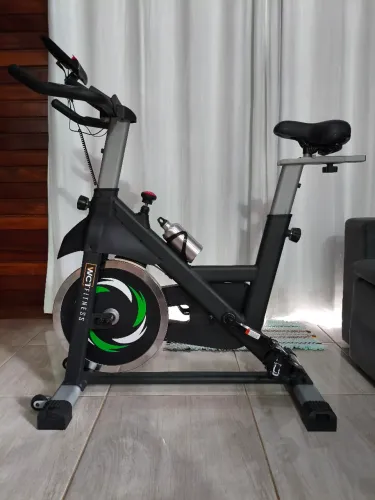 Bicicleta Ergométrica Spinning 20kg WCT Fitness na cor preto e verde.