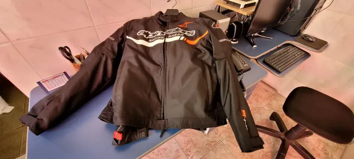 Produtos para motociclista, sendo uma jaqueta Alpinestars, um capacete e um par de luvas.